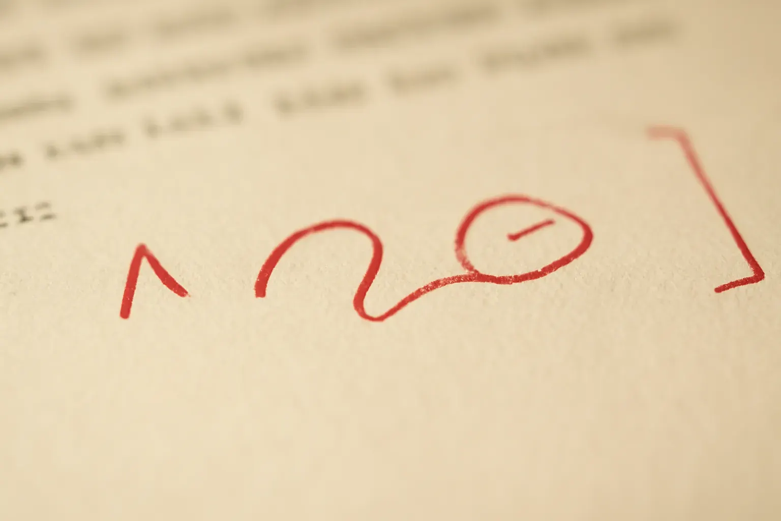 A red pen resting on a page of proofread copy, corrections marked in the margin.